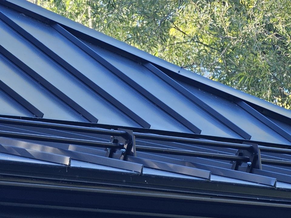 Snow guard row on black standing seam roof, Milton Ontario residential project
