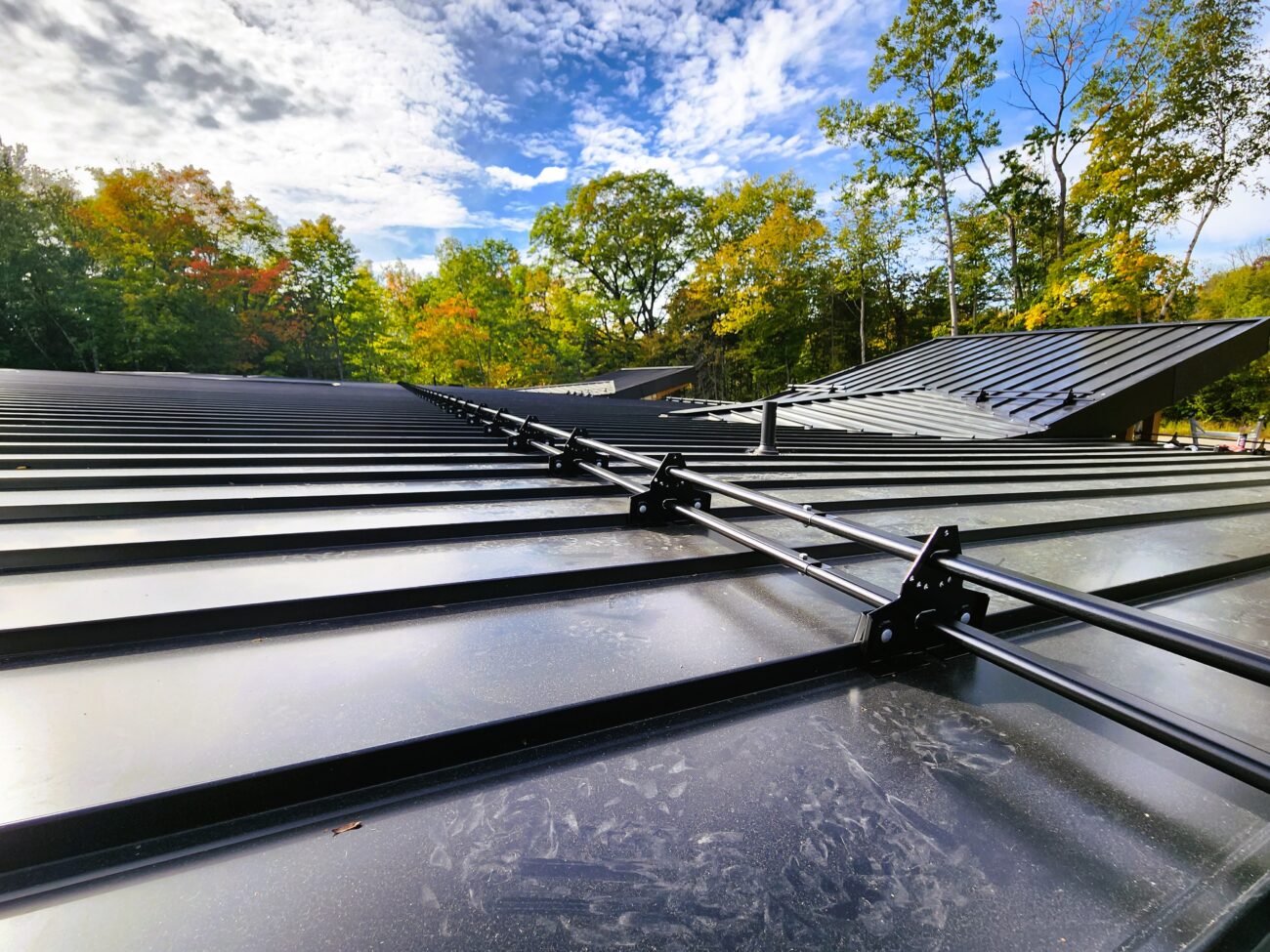 Two rows of ORIMA LE2SL snow guards on black standing seam roof, Muskoka Ontario cottage