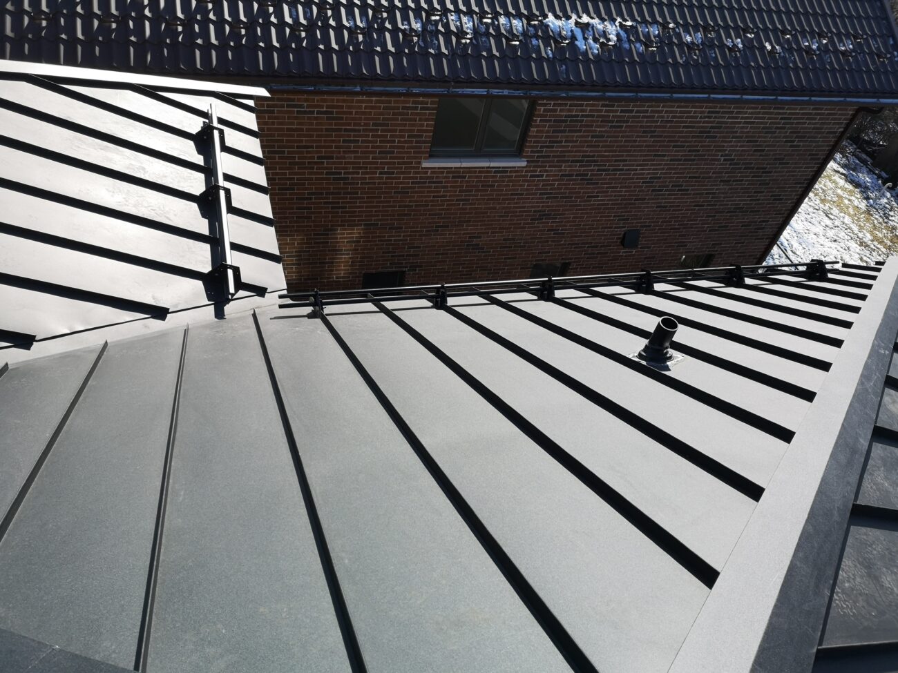 Black steel tubular snow guards installed on snap-lock standing seam roof in Scarborough, Toronto