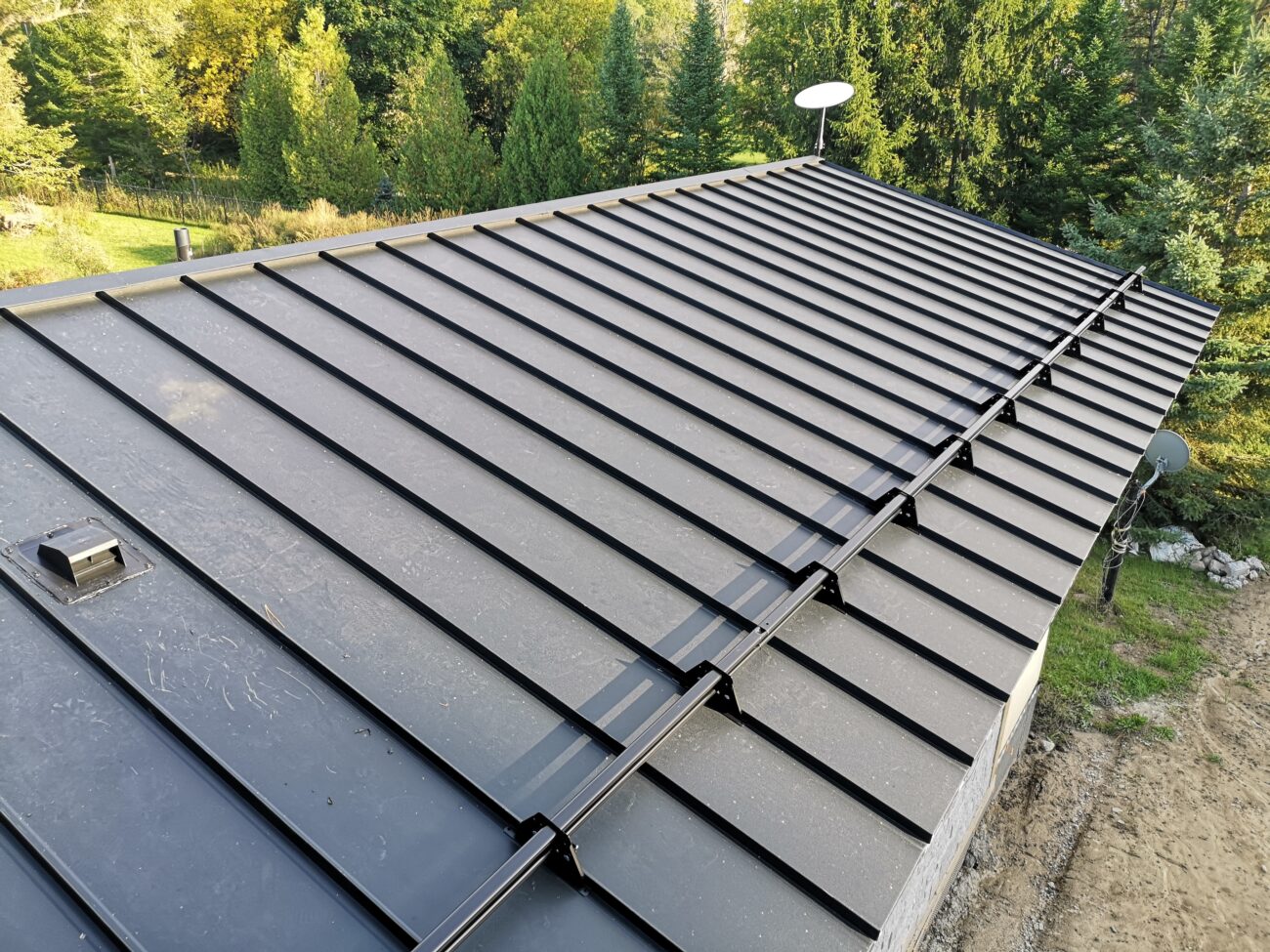 Steel snow guard clamp detail on black snap-lock standing seam roof, Uxbridge Ontario