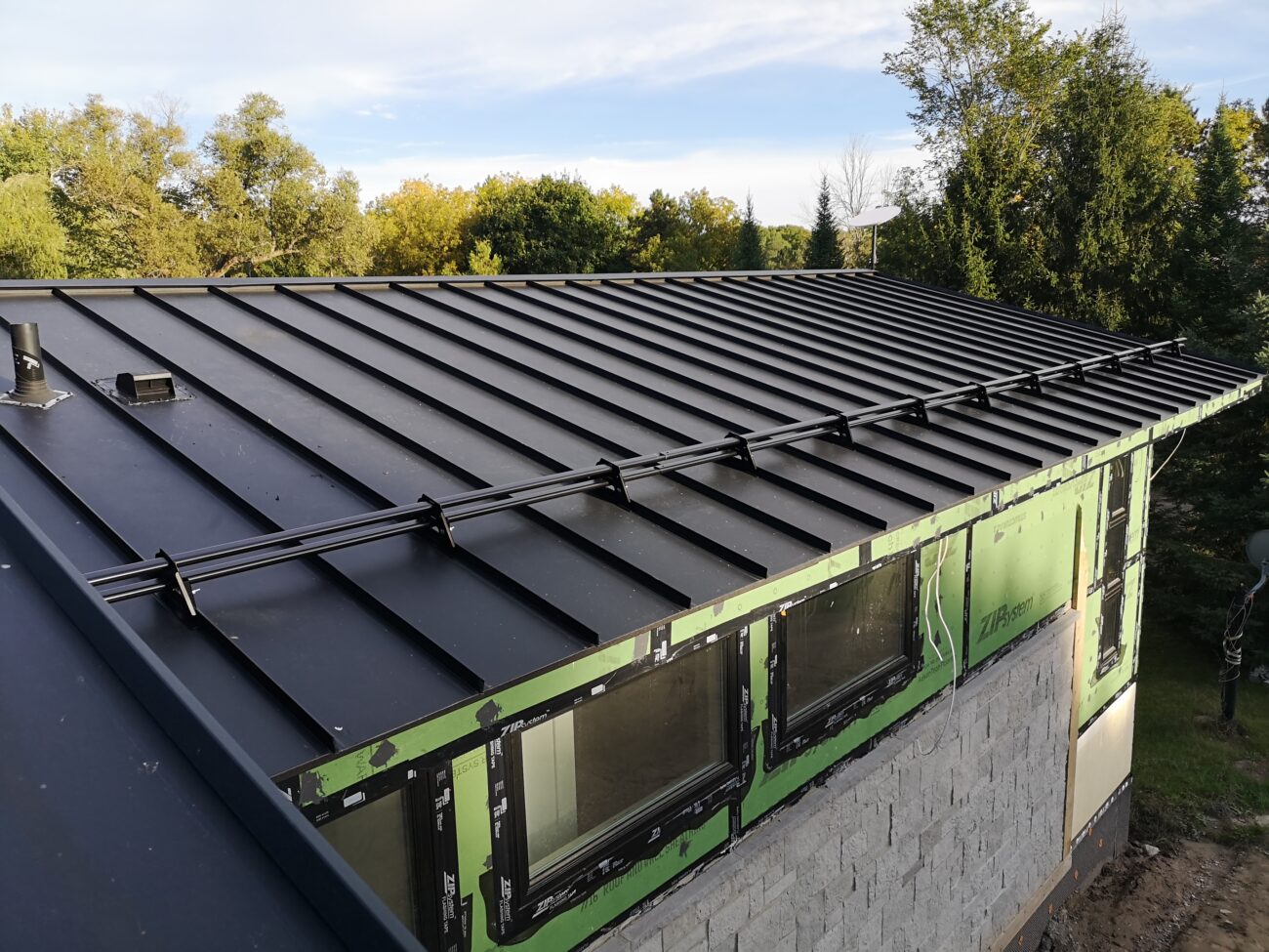 Steel snow guard row on black standing seam roof, Uxbridge Ontario residential project