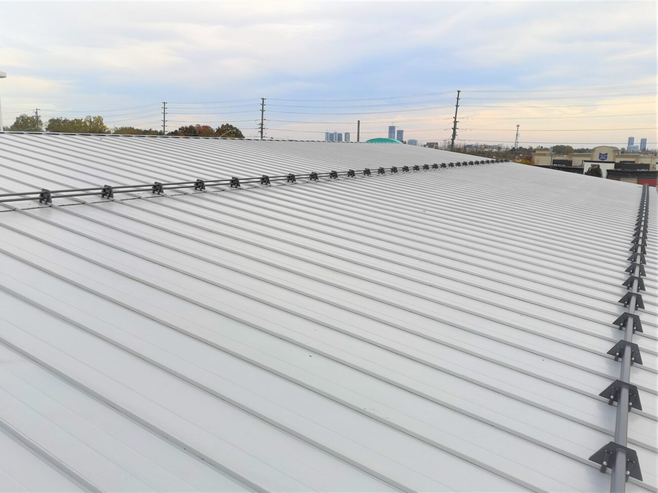 Grey steel snow guard row on commercial standing seam roof, Vaughan Ontario